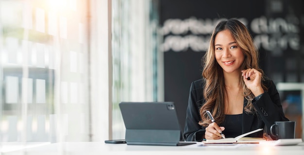 Jeune belle et charmante femme d'affaires asiatique souriante et travaillant sur un ordinateur portable au bureau