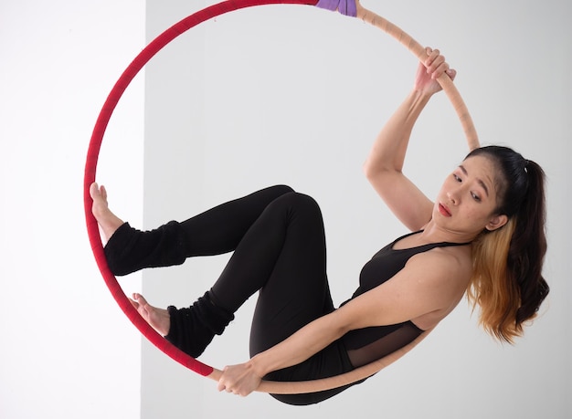 Jeune belle danseuse asiatique vêtue de couleur noire exécutant une danse aérienne avec un cerceau aérien au studioxA