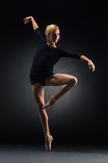 Jeune belle danseuse de style moderne posant sur un fond gris de studio