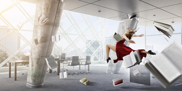 Jeune et belle danseuse vêtue d'une robe rouge sautant avec des livres qui volent. Technique mixte