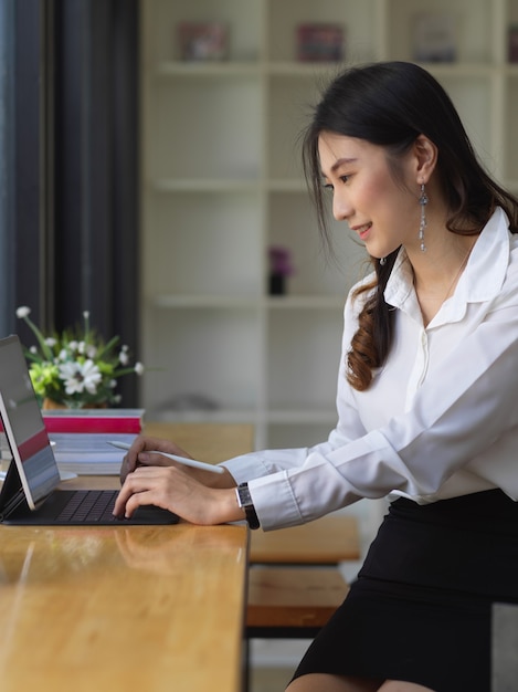 Jeune belle employée de bureau travaillant avec tablette numérique