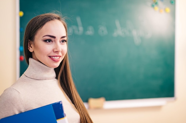 Jeune belle enseignante en classe Enseignant tenant un dossier dans la salle de classe de l'école ou de l'université Concept d'éducation et d'emploi