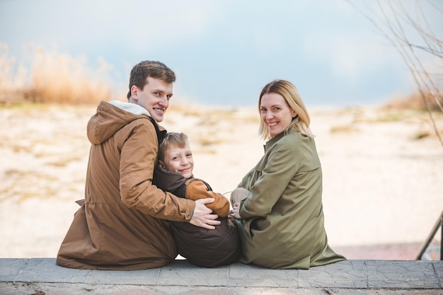 Jeune belle famille assise sur la plage avec vue sur le lac