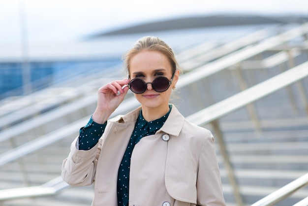 Jeune belle femme d'affaires avec lunettes de soleil, téléphone, ordinateur portable, tasse de café dans les rues de la ville.