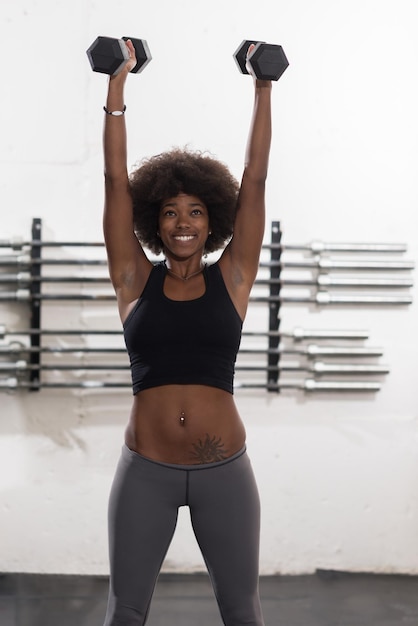 jeune belle femme afro-américaine faisant des boucles de biceps dans une salle de sport