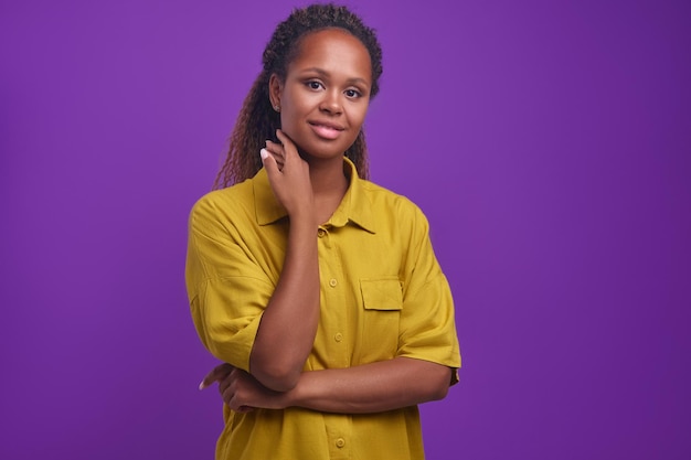 Jeune belle femme afro-américaine optimiste se tient en studio violet