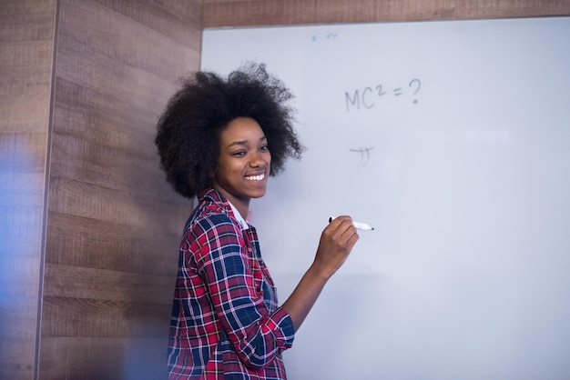 Jeune belle femme afro-américaine réussie écrit sur une réunion du conseil d'administration dans un grand bureau moderne