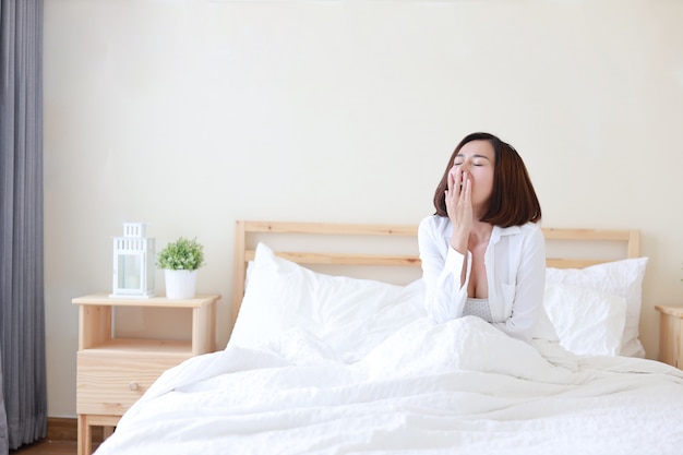 Jeune Belle Femme Asiatique, Cheveux Courts Se Réveillant Sur Le Lit Et Bâillant Le Matin Dans La Chambre