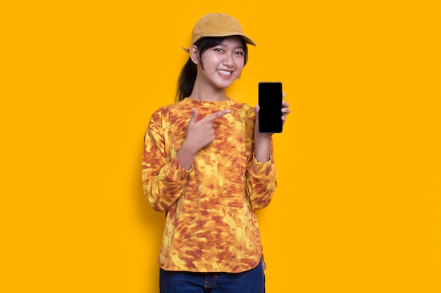 jeune belle femme asiatique démontrant un téléphone portable isolé sur fond jaune