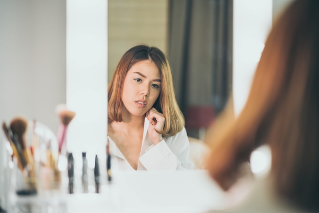Jeune belle femme asiatique maquillant près d&#39;un miroir
