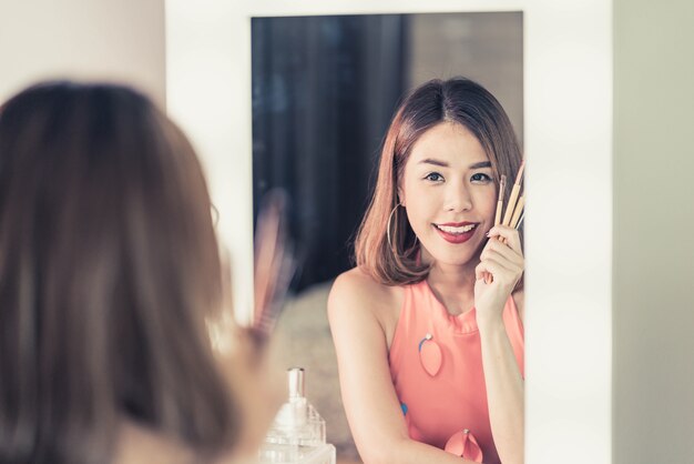 Jeune belle femme asiatique maquillant près d&#39;un miroir