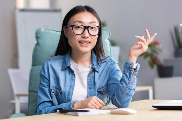 Jeune belle femme asiatique parlant sur appel vidéo femme d'affaires travaillant dans un bureau moderne souriant