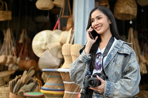 Jeune belle femme asiatique parlant au téléphone au marché en voyageant