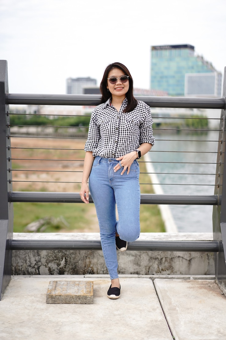 Photo jeune belle femme asiatique portant une chemise à carreaux et un jean bleu posant à l'extérieur