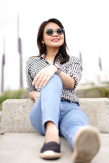 Jeune belle femme asiatique portant une chemise à carreaux et un jean bleu posant à l'extérieur