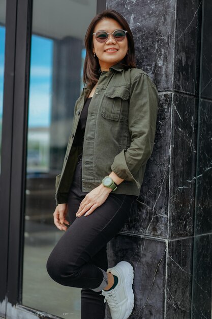 Jeune belle femme asiatique portant une veste et un jean noir posant à l'extérieur