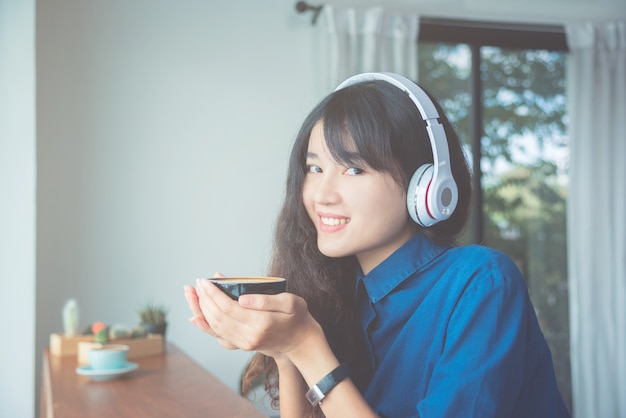 Jeune belle femme asiatique tenant une tasse de café et des sourires