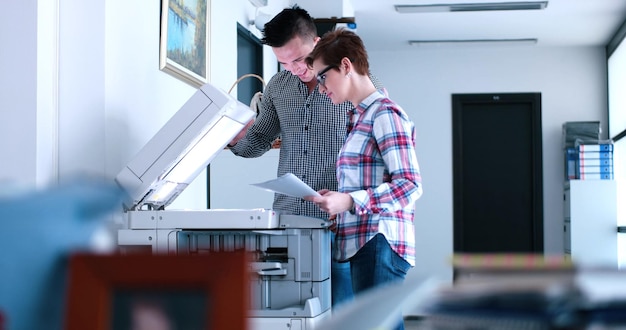 Jeune belle femme avec assistant faisant des copies de fichiers dans la photocopieuse