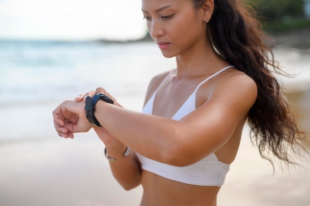 Jeune belle femme en bikini se détendre et utiliser une montre intelligente sur la plage