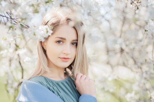 Jeune belle femme blonde dans un jardin fleuri de sakura