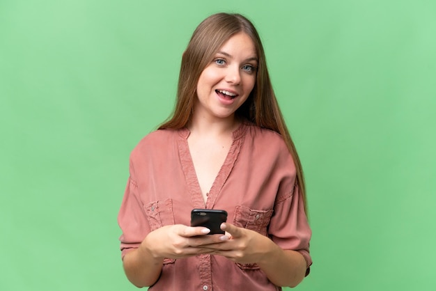 Jeune belle femme blonde sur fond isolé surpris et envoyant un message