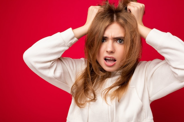 Jeune belle femme blonde insatisfaite en colère avec des émotions sincères isolées sur fond avec