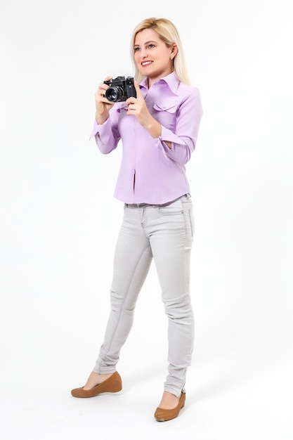 Jeune belle femme blonde souriante tenant un appareil photo micro quatre tiers. Isolé sur fond blanc.