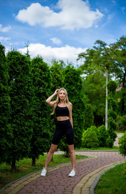 Jeune belle femme blonde sportive dans un T-shirt noir et en short de sport moulant noir