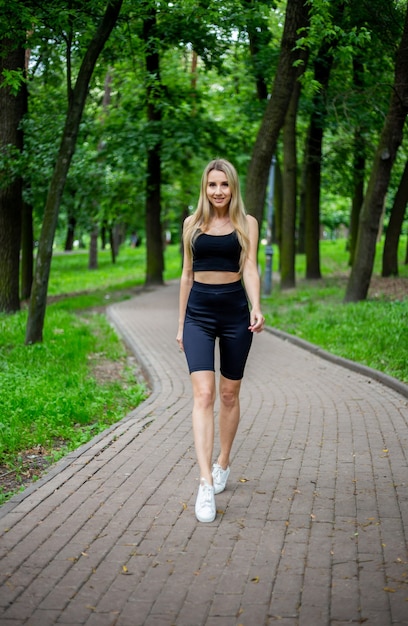 Jeune belle femme blonde sportive dans un T-shirt noir et en short de sport moulant noir