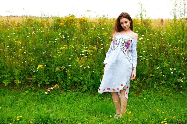 Photo jeune belle femme brune en robe blanche d'été sur fond de parc d'herbe verte d'été