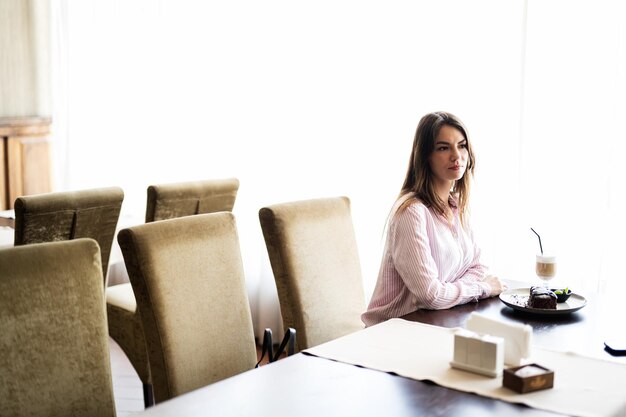 Jeune belle femme brune s'asseoir dans un café-restaurant café à l'intérieur