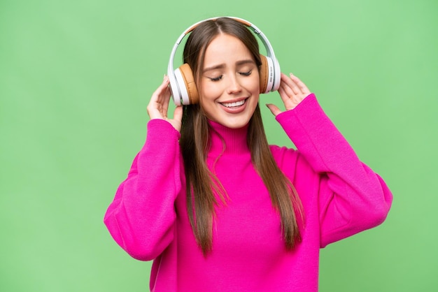 Jeune belle femme caucasienne sur fond isolé écoutant de la musique et chantant