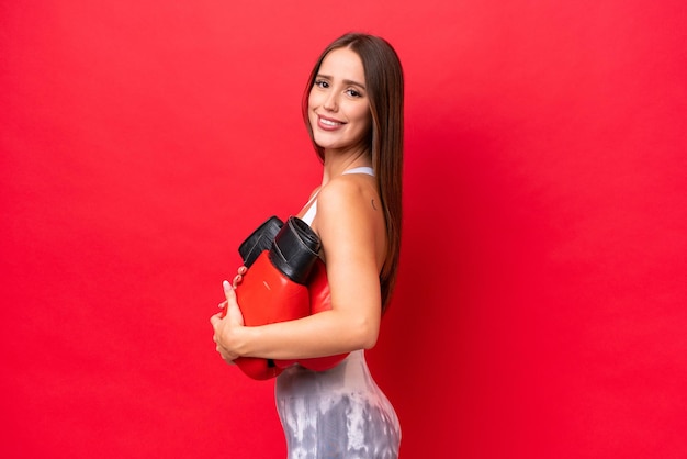 Jeune belle femme caucasienne isolée sur fond rouge avec des gants de boxe