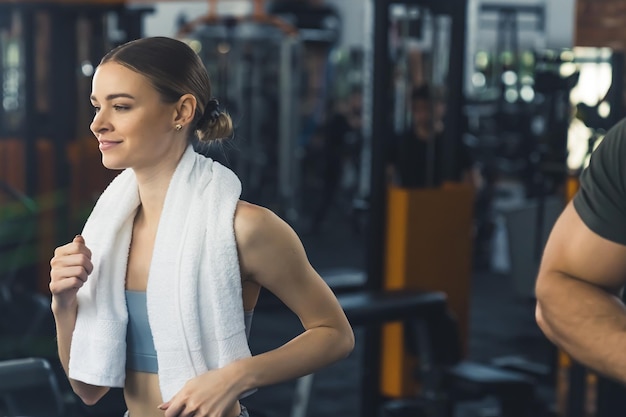 Jeune belle femme caucasienne mince aux cheveux blonds en chignon travaillant dans la salle de gym ayant un blanc