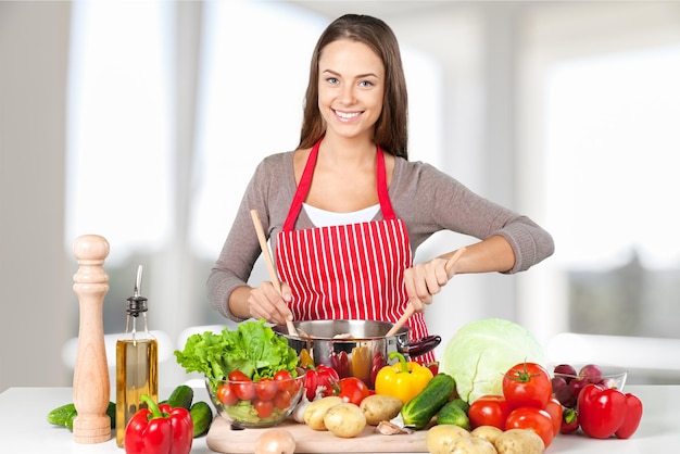 Jeune belle femme avec la cuisine de légumes frais