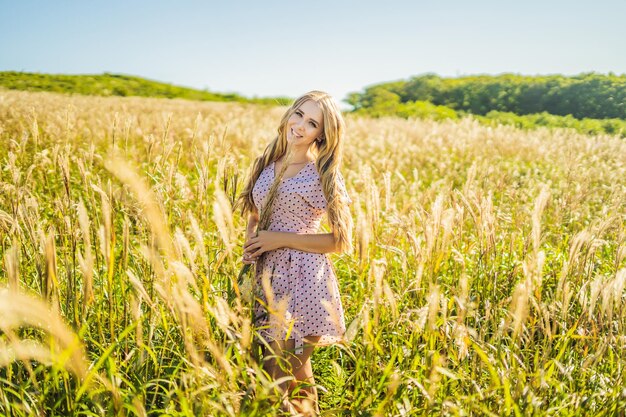 Jeune belle femme dans un paysage d'automne avec des fleurs sèches épis de blé Mode automne hiver Ensoleillé automne photo de mode