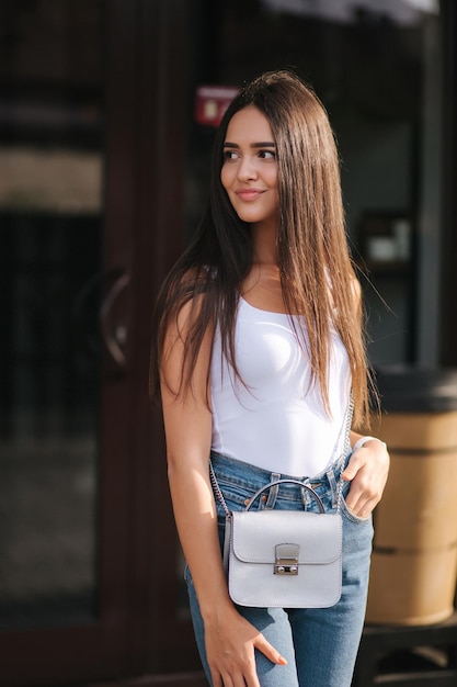 Jeune et belle femme debout à l'extérieur devant le café Jolie brune en chemise blanche