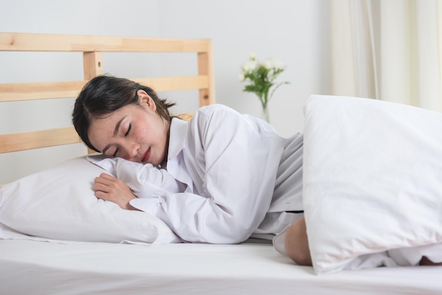 Jeune belle femme dormant sur un lit blanc à la maison