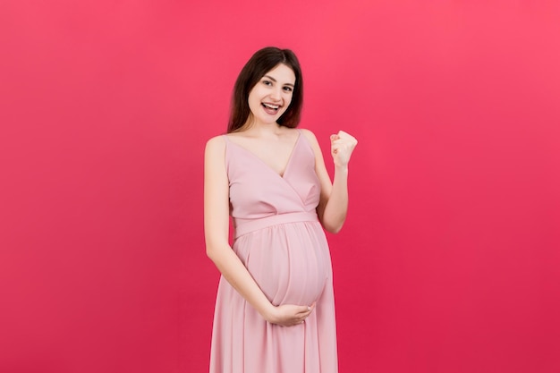 Jeune belle femme enceinte sur fond coloré isolé célébrant surpris et étonnés pour le succès avec les bras levés et les yeux ouverts concept gagnant