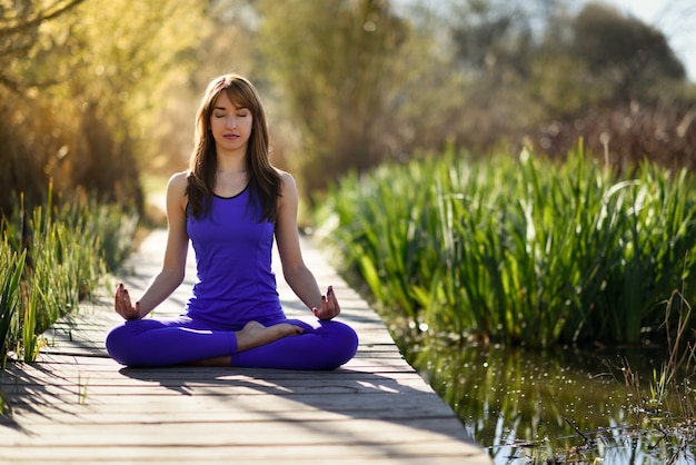 Jeune belle femme faisant du yoga dans la nature