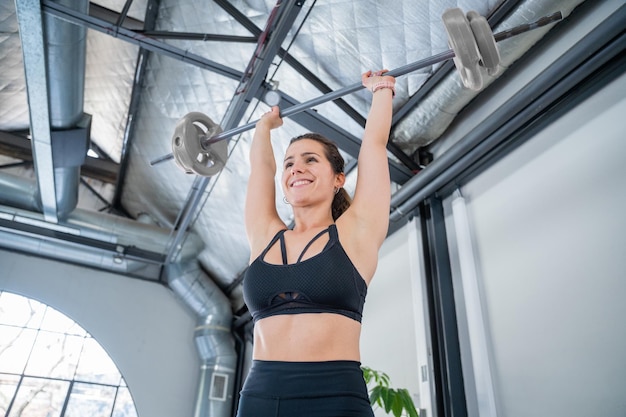 Jeune et belle femme faisant de l'exercice avec bar à la maison