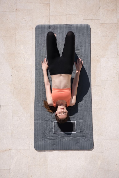 jeune belle femme faisant des exercices de yoga le matin devant sa maison de luxe villa vue de dessus