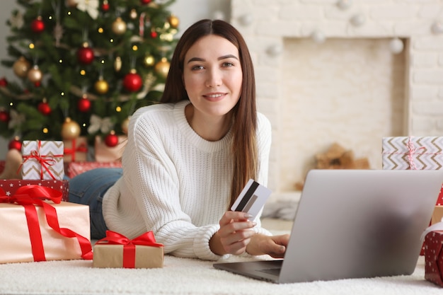 La jeune belle femme fait des emplettes pour Noël dans l'intérieur de fête à la maison