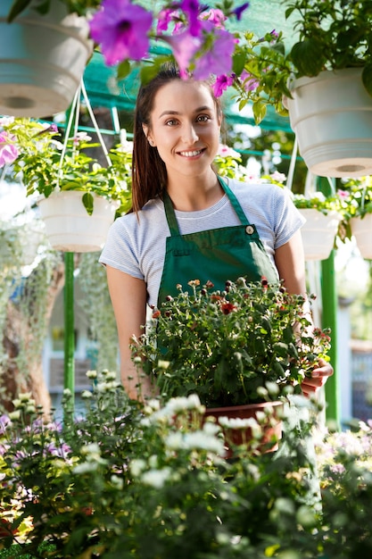 Jeune belle femme fleuriste posant, souriant parmi les fleurs.