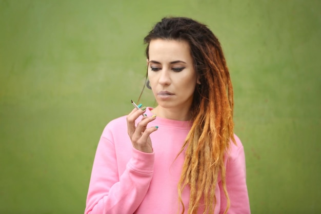 Jeune belle femme fumant de l'herbe sur un fond de couleur