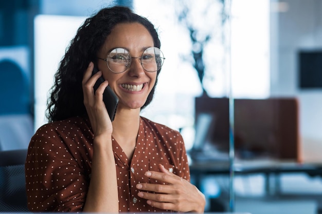 Jeune et belle femme hispanique parlant au téléphone et souriante femme d'affaires heureuse se bouchent dans