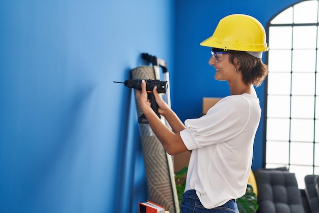 Jeune belle femme hispanique souriant mur de forage confiant à la nouvelle maison