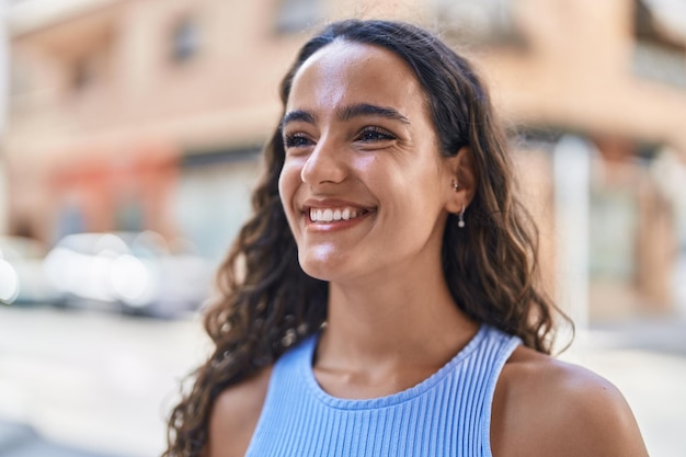 Jeune belle femme hispanique souriante confiante regardant sur le côté dans la rue