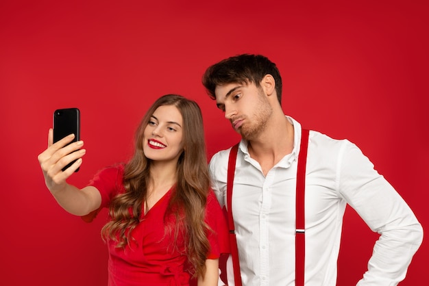 Jeune belle femme et homme embrassent dans des tenues élégantes prenant selfie