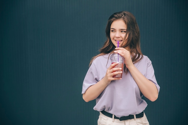 Jeune belle femme incroyable buvant de la limonade et posant